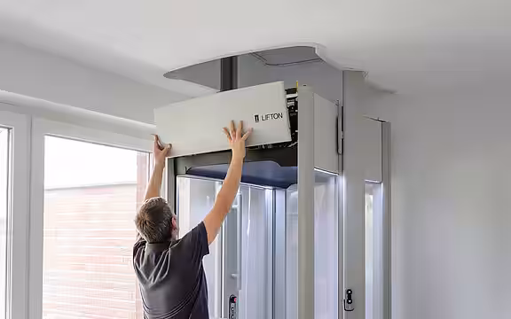 Ein Mitarbeiter von LIFTON bringt die Verkleidung an das Elektronikgehäuse des Homelifts an.