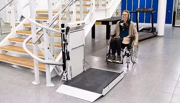 Eine Rollstuhlfahrerin fährt auf einen Plattformlift